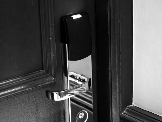 Brass keycard door lock with a green indicator light on a dark panelled door