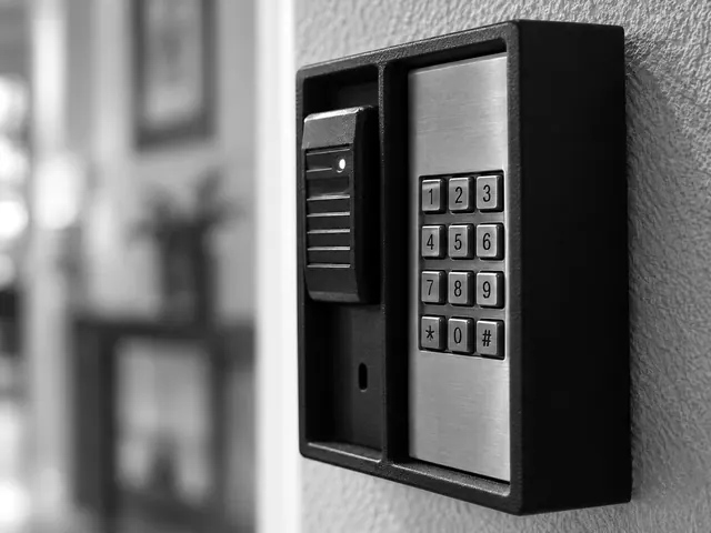 Wall-mounted brass keypad lockbox with card reader in an office hallway