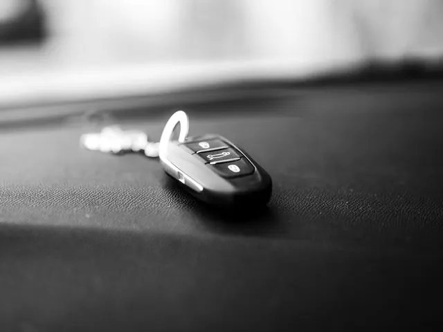 Three-button remote car key fob lying on a dashboard